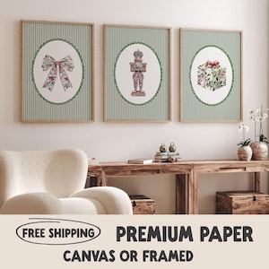 May include: Three framed prints with a Christmas theme. Each print features a different design: a bow, a nutcracker, and a gift box, all set against a green and white striped background. The prints are in wooden frames.