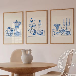 May include: Three framed prints with blue illustrations of breakfast, wine, and a candlelit dinner. Each print features a white background and a wooden frame.