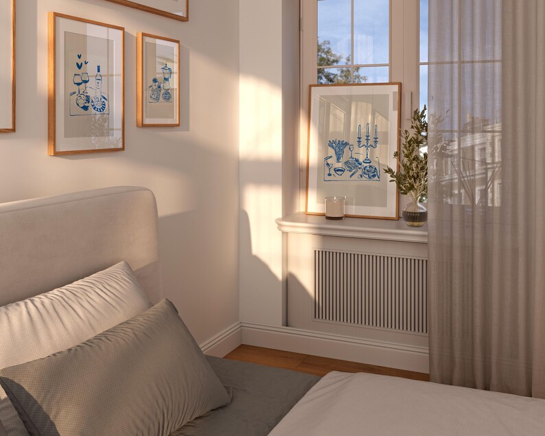 May include: A bedroom with a white bed, a white headboard, and two pillows. There are three framed pictures on the wall above the bed. A window with white curtains is on the right side of the image. The windowsill has a framed picture and a candle.