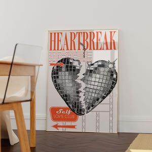 Pode incluir: Uma impress&atilde;o emoldurada com um cora&ccedil;&atilde;o de bola de discoteca quebrado no centro. O texto "HEARTBREAK HOTEL" est&aacute; no topo da impress&atilde;o. O texto "Self Love Club" est&aacute; em uma faixa vermelha na parte inferior da impress&atilde;o.