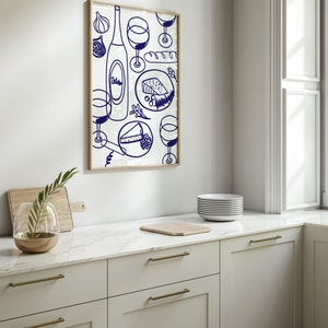 May include: A framed illustration of a wine bottle, glasses, cheese, and bread in a blue and white color scheme. The illustration is on a white background and is framed in a light wood frame.