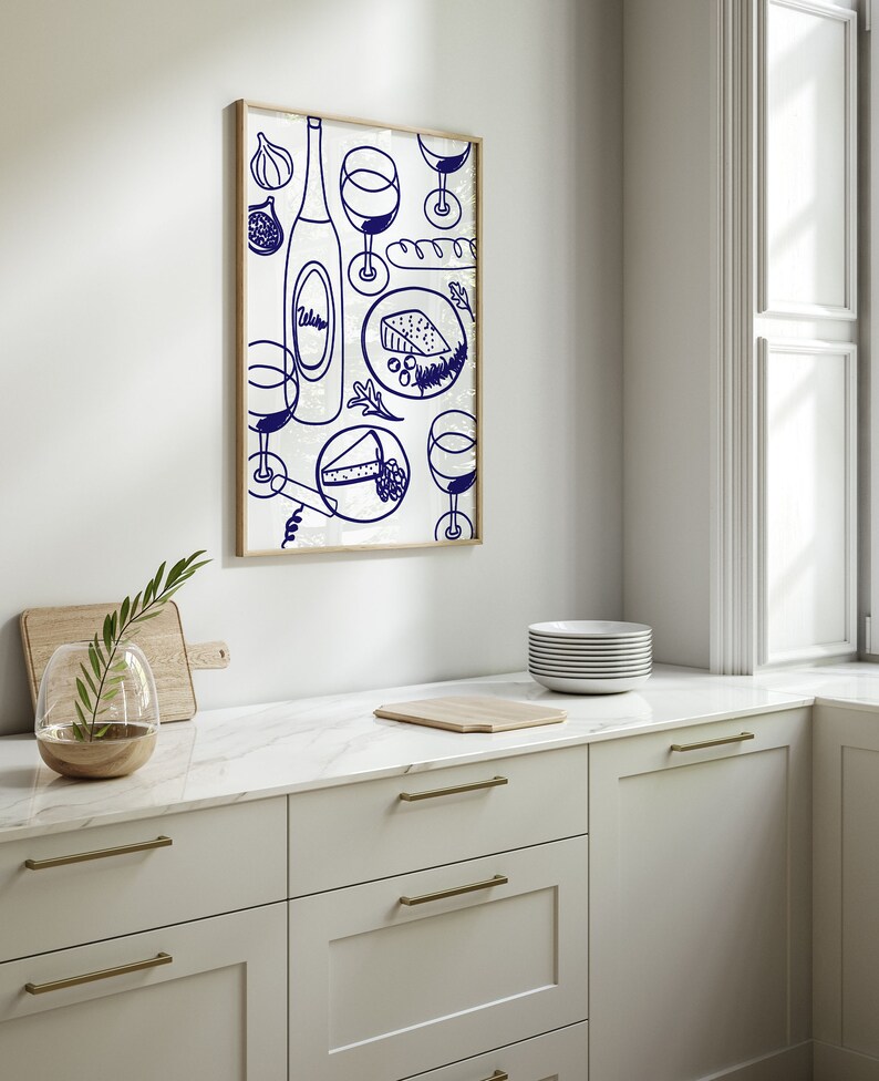 May include: A framed illustration of a wine bottle, glasses, cheese, and bread in a blue and white color scheme. The illustration is on a white background and is framed in a light wood frame.