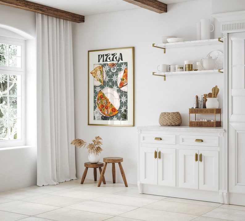 May include: A framed print of a pizza with the word "Pizza" in a stylized font. The print is hanging on a white wall in a kitchen setting. The kitchen features white cabinets, a white countertop, and gold shelves.