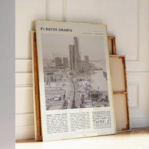 K&ouml;nnte beinhalten: Ein gerahmter Schwarz-Wei&szlig;-Druck mit dem Titel "F1 Saudi Arabia", der eine Stadtlandschaft und eine Rennstrecke zeigt. Der Druck enth&auml;lt Text mit Details zum Rennen, einschlie&szlig;lich der Anzahl der Runden und Kurven. Der Druck wird mit anderen gerahmten Kunstwerken ausgestellt.