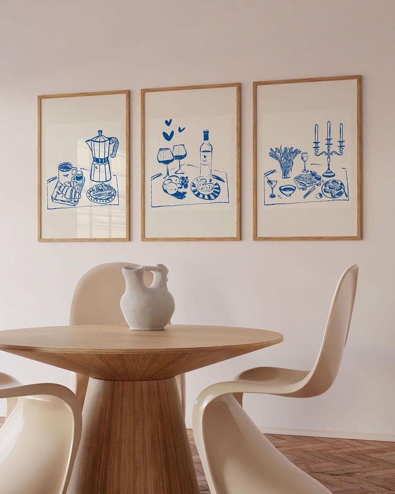 May include: Three framed illustrations of a romantic breakfast in bed scene. The illustrations are in blue ink on a white background. The first illustration shows a coffee pot, a cup of coffee, a croissant, and a plate of fruit. The second illustration shows a bottle of wine, two glasses of wine, a plate of fruit, and a plate of bread. The third illustration shows a plate of food, a glass of wine, a candle holder with three candles, and a vase of flowers.