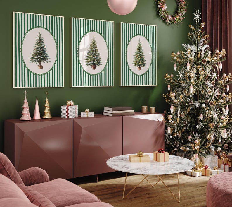 May include: Three framed Christmas tree prints with green and white striped backgrounds hang above a burgundy cabinet. A decorated Christmas tree stands to the right, with a marble coffee table in front.