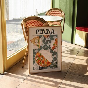 May include: A framed poster with the word "PIZZA" in a retro font. The poster features a close-up of three slices of pizza on a green and white tiled surface.