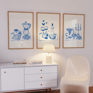 May include: Three framed illustrations of blue line drawings depicting different meals on trays. The first illustration shows a coffee pot, coffee cup, and pastries. The second illustration shows a bottle of wine, two glasses of wine, and a plate of food. The third illustration shows a plate of food, a glass of wine, and a candelabra with candles.