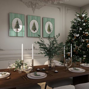 May include: A festive Christmas dining scene. Three framed artworks with green striped backgrounds and Christmas tree images hang above a table set for a holiday meal. A decorated Christmas tree and candles complete the holiday ambiance.