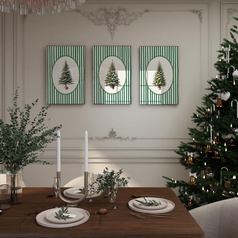 May include: Three framed Christmas tree art pieces with green and white striped backgrounds. The art is displayed above a wooden dining table set for a holiday meal. A decorated Christmas tree is in the background.