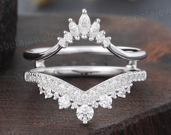 May include: A delicate silver ring with a crown-shaped design and a V-shaped band, both adorned with sparkling clear gemstones.