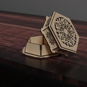 May include: A wooden box with a decorative, intricate, laser-cut design on the lid. The box is open and the lid is lying on the table next to the box.