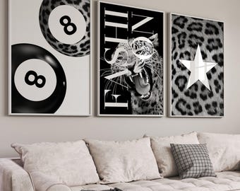May include: Three framed wall art pieces. The first features two black and white 8-ball pool balls. The second has a leopard with the word "FASHION" and glasses. The third has a leopard print background with a white star. The art is displayed above a beige sofa.