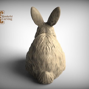 A wooden rabbit statue with large ears, sitting on a plain background.