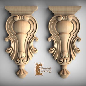 May include: Two wooden decorative corbels with an ornate, symmetrical design. Each corbel features a scrolled pattern, a central vase-like shape, and a decorative base. The corbels are made of light-colored wood and are displayed against a neutral background.