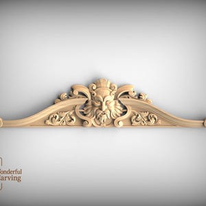Peut inclure: Élément architectural décoratif en bois sculpté, orné d'un visage central couronné, flanqué de volutes et de motifs floraux. La pièce, de forme incurvée, est probablement destinée à l'ameublement ou à la décoration murale.