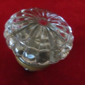 May include: A clear glass door knob with a decorative, faceted design. The knob has a brass base.