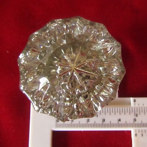 May include: A clear glass door knob with a faceted design. The knob is approximately 2 inches in diameter.