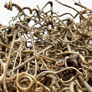 May include: A close-up of a pile of dried, twisted, brown vines. The vines are tangled together in a random pattern, creating a textured and organic look.