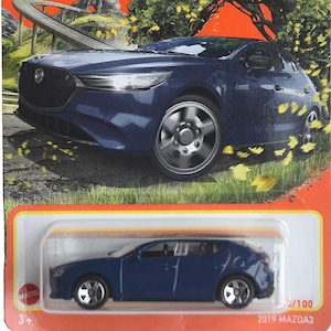 May include: A dark blue 2019 Mazda3 Matchbox toy car on an orange card. The packaging features the Matchbox logo and "70 Years" text. The car is approximately 7.6 cm long and is part of the 0/100 series.