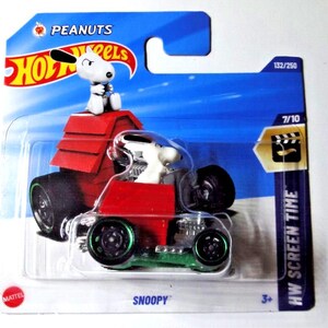 Op de afbeelding: Een Hot Wheels Snoopy-auto met een rood hondenhuisontwerp en een Snoopy-figuur. De auto heeft zwarte wielen met groene velgen, verpakt in een blauwe en transparante blisterverpakking. De verpakking bevat de tekst "PEANUTS" en "HW SCREEN TIME".