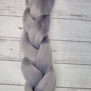 Puede incluir: Una trenza larga de pelo sintético gris con una banda elástica en el extremo.