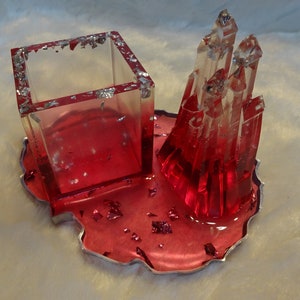 May include: A red resin tray with a clear resin crystal tower and a square clear resin container. The tray has silver glitter embedded in the resin.