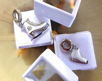 Peut inclure: Deux breloques en argent en forme de patins à glace avec émail blanc et accents de cristal transparent. Les breloques sont présentées dans des boîtes blanches.