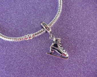 Peut inclure: Bracelet à breloques en argent avec un charme de patins à glace en argent. Le charme est détaillé avec une sangle noire et une lame argentée.