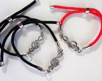 Peut inclure: Trois bracelets réglables. Deux sont noirs et un est rouge. Chaque bracelet comporte un charm en forme de clé de sol argenté orné de strass transparents. Les bracelets ont des embouts en métal argenté et des nœuds coulissants réglables.