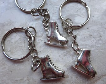 May include: Three silver keychains with ice skate charms. Each keychain has a silver ring and a silver chain. The ice skate charms are detailed with a silver blade and a silver boot.