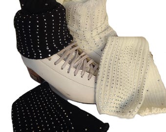May include: White ice skates with black and cream-colored leg warmers. The leg warmers are embellished with silver rhinestones. The black leg warmers are folded over. The cream-colored leg warmers are straight. The skates have white laces.