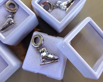 Peut inclure: Un charme en argent en forme de patin à glace avec des détails bleus et blancs. Le charme est dans une petite boîte blanche avec un couvercle transparent. Le charme porte le numéro "S925" gravé dessus.