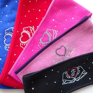 Könnte beinhalten: Fünf Fleece-Stirnbänder mit einem Strass-Kronen- und Herz-Design. Die Stirnbänder sind in Blau, Rot, Rosa, Hellrosa und Schwarz.