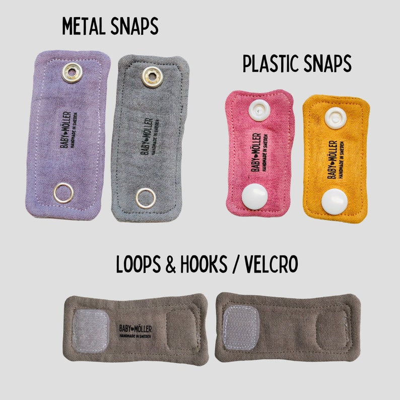 May include: Rectangular fabric straps labeled BABY M&Ouml;LLER HANDMADE IN SWEDEN. Top left: two purple and gray straps with metal snaps. Top right: two pink and yellow straps with plastic snaps. Bottom: two brown straps with hook and loop fasteners.