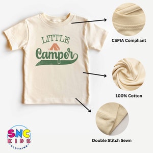 Puede incluir: Camiseta color crema con las palabras "Little Camper" en verde y naranja. La camiseta est&aacute; hecha de 100% algod&oacute;n y tiene costuras dobles. La camiseta cumple con CSPIA.