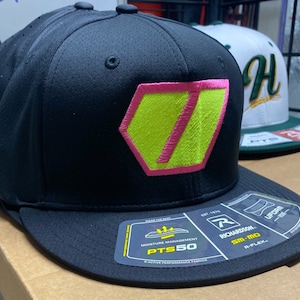 Peut inclure: Casquette de baseball noire avec un logo vert néon et rose. Le logo est un hexagone avec une ligne diagonale qui le traverse. La casquette a une visière noire et un dos en maille noire. La casquette a une étiquette sur la visière qui dit "Richardson" et "PTS50".