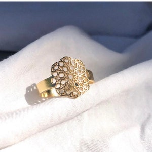 Könnte beinhalten: Ein goldener Ring mit geometrischem Design. Der Ring ist aus Metall gefertigt und hat ein filigranes, kompliziertes Muster.