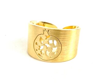 May include: A gold-toned ring with a cutout design of a pomegranate. The ring is made of metal and has a brushed finish.