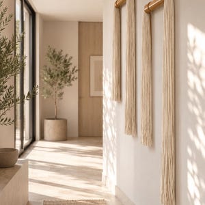 Minimalist tassel wall hanging in neutral cotton and bamboo displayed in a modern Japandi living room, above wooden console, soft natural tones, luxury home decor