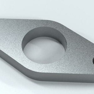 May include: A silver metal spacer with a large center hole and two smaller holes on the sides. The spacer is designed to fit between two pipes or other components.
