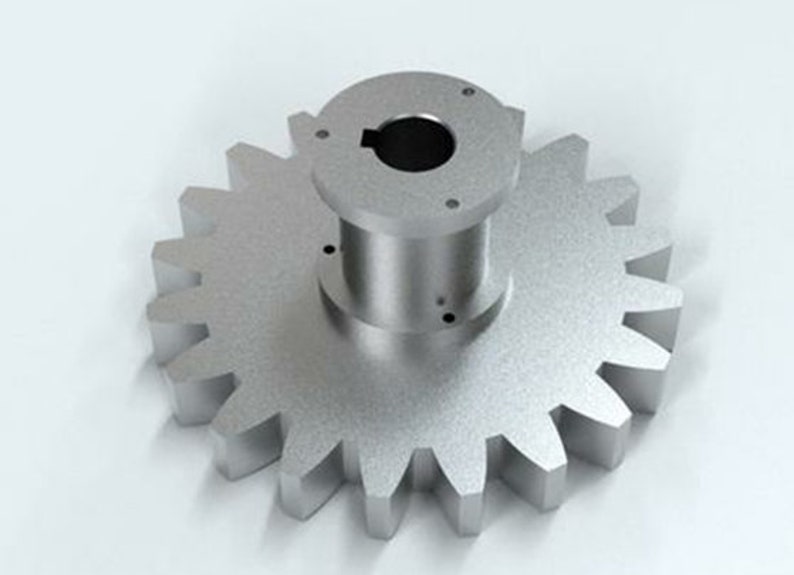 May include: A silver metal gear with a central hub and a series of teeth around the outer edge. The gear is designed to mesh with other gears to transmit power.