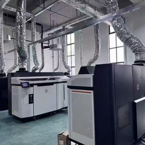 May include: An industrial interior with multiple large HP printers in white and black. The printers are linked to silver ventilation ducts. The room has large windows and a concrete floor. The overall aesthetic is modern and functional.