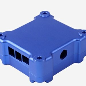 May include: A blue aluminum case with a rectangular shape and rounded edges. The case has a series of rectangular openings on one side and a circular opening on another side.