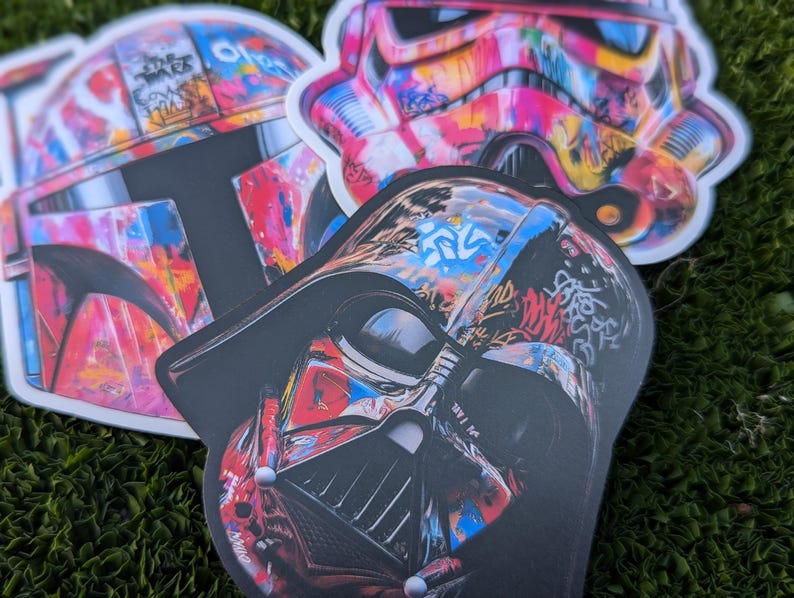May include: Three colorful Star Wars character stickers with a graffiti design. The stickers feature Darth Vader, Boba Fett, and a Stormtrooper.