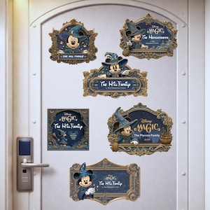 May include: A collection of navy blue and gold decorative plaques featuring Mickey Mouse in a wizard hat. The plaques have ornate frames and include text such as "Disney Magic" and family names. The plaques are affixed to a white door.