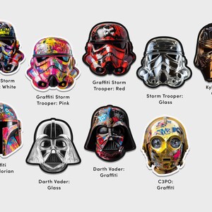 May include: A collection of Star Wars character helmets decorated with colorful graffiti art. The helmets include Stormtroopers, Darth Vader, Kylo Ren, and C3PO. The helmets are displayed on a white background.