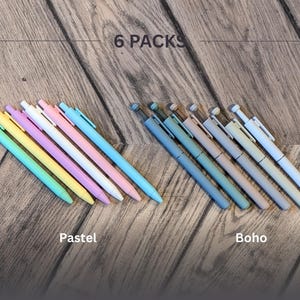 May include: Two sets of six pastel colored pens, one set in shades of blue, green, yellow, and pink, and the other set in shades of gray, beige, and brown. The text "6 PACKS" is above the pens, and the words "Pastel" and "Boho" are below the pens.