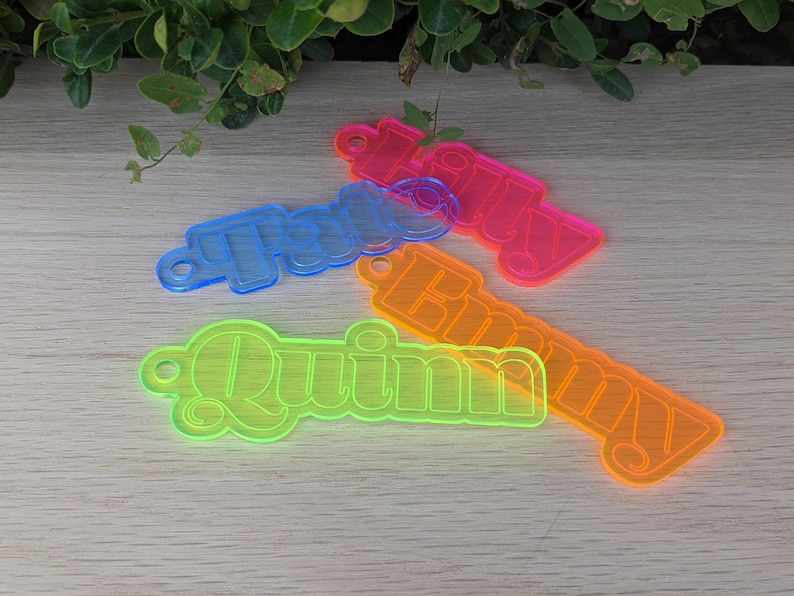 May include: Four neon-colored acrylic keychains with the names "Quinn", "Emily", "Faith", and "Lily" written in a retro font.