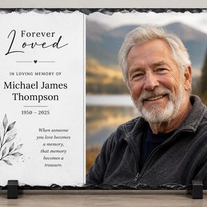 May include: A rectangular slate memorial plaque with rough, jagged edges. The left side features the text Forever Loved, In Loving Memory of Michael James Thompson, 1950-2025, and a quote with a leaf illustration. The right side displays a portrait of a man.